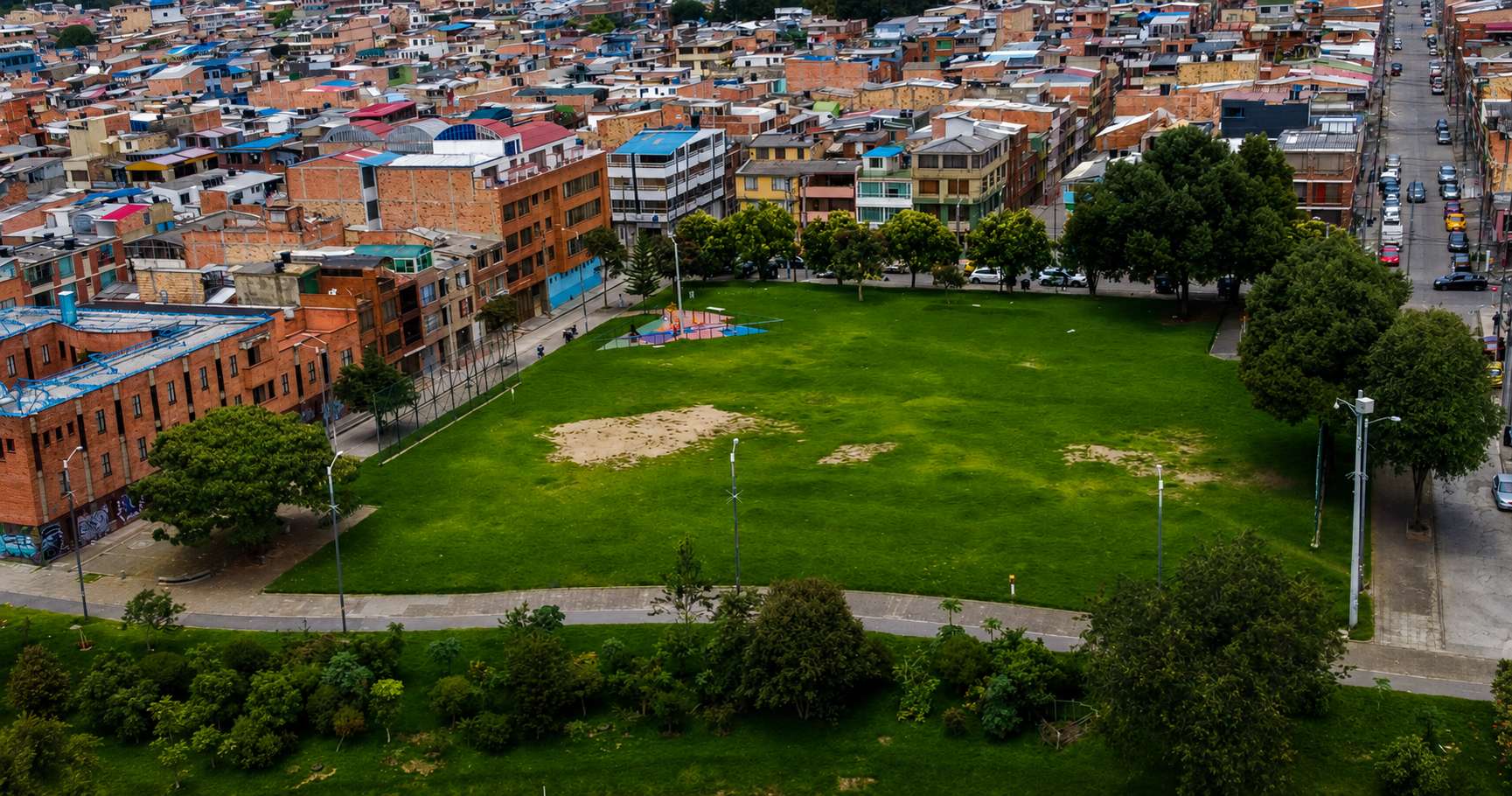 Aerial view of Bosques de Mariana neighborhood park before its transformation, showing disconnected recreational areas next to the Jaboque wetland in Bogotá, Colombia.