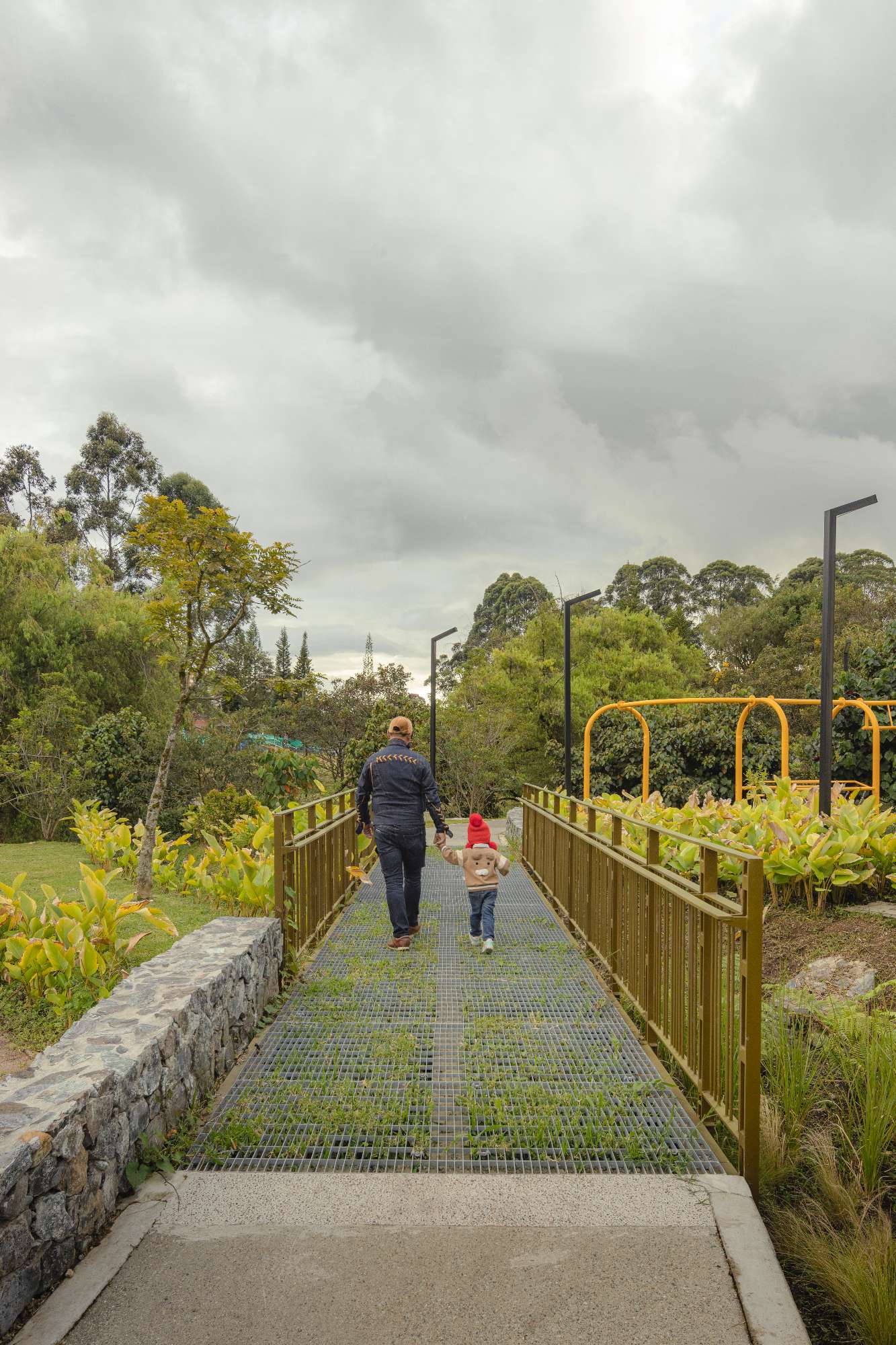 Pedestrian bridge crossing a memorial landscape, reinforcing the relationship between water, memory and community.